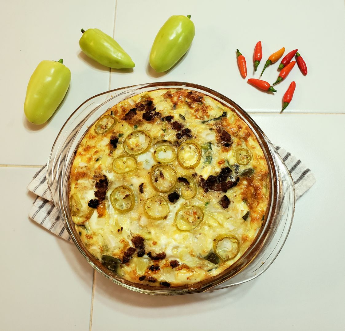 a top down view of a cream cheese quiche surrounded by tabasco and sweet peppers