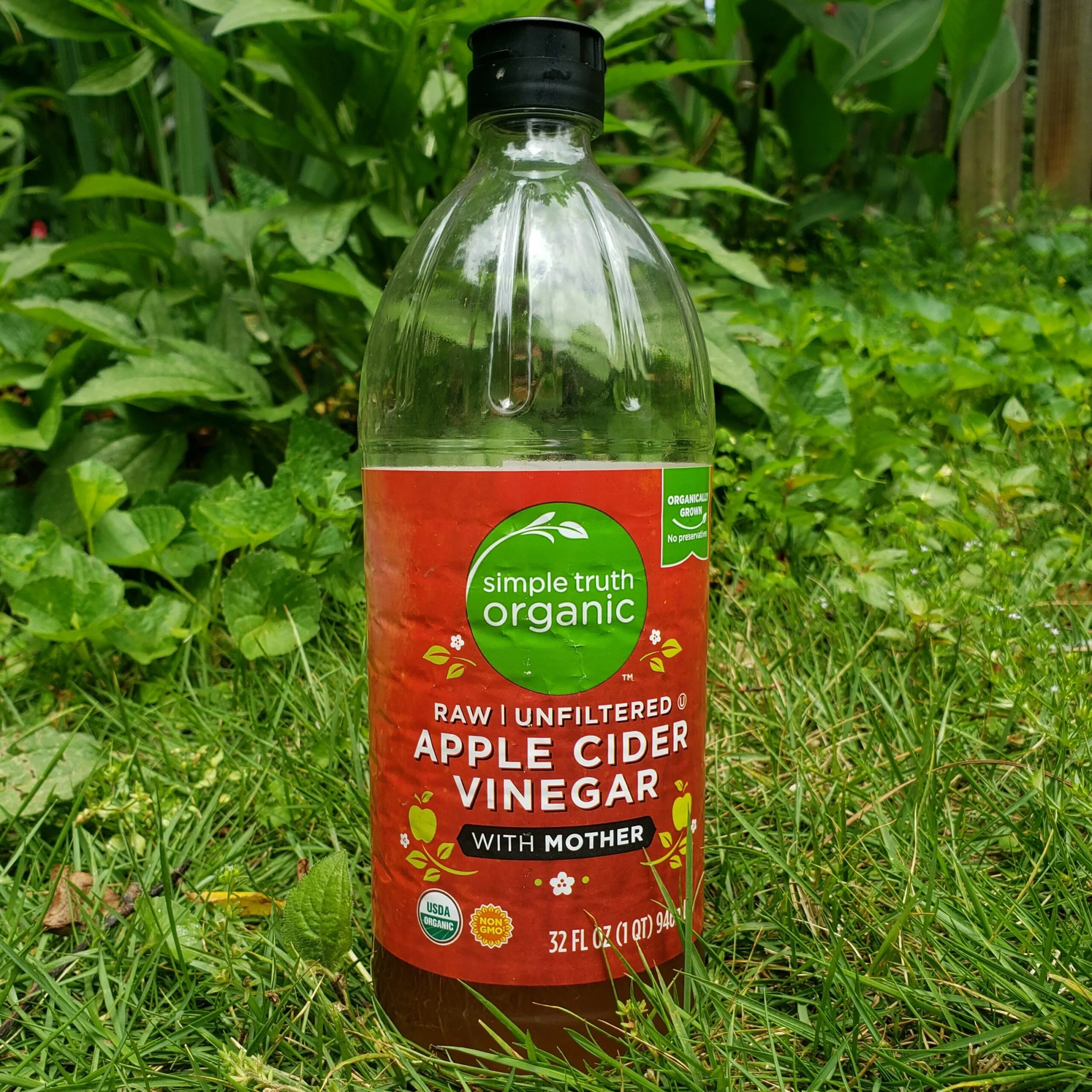 a bottle of apple cider vinegar against a garden backdrop